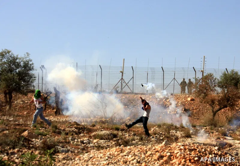 Palestinian youths run for cover from tear gas canister fired by Israeli soldiers during a demonstration against Israel's separation barrier in the West Bank village of Bilin near Ramallah, Friday,Nov. 4, 2010. Photo by...