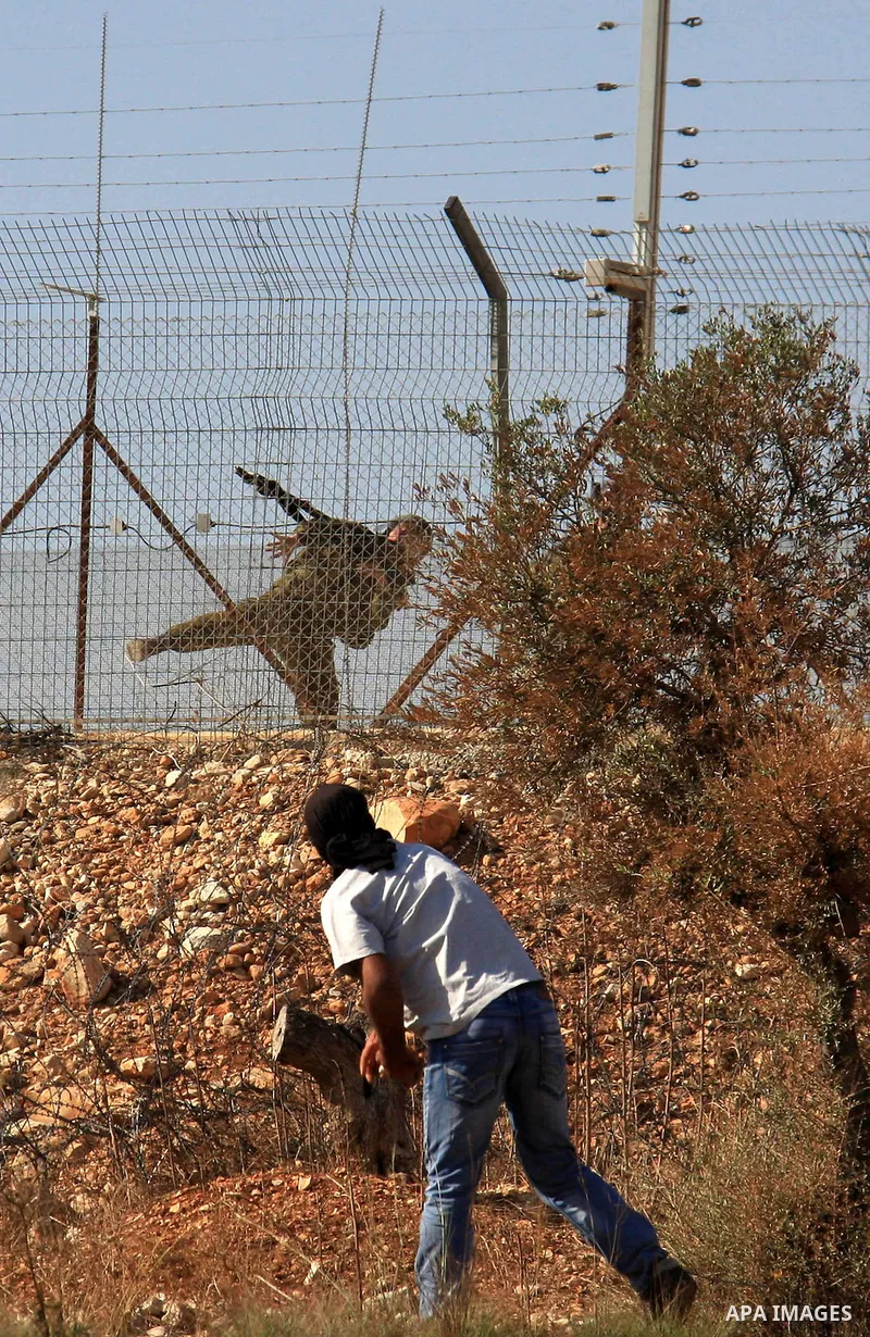 A Palestinian protestor uses a slingshot to throw rocks at Israeli soldiers during a demonstration against Israel's separation barrier in the West Bank village of Bilin near Ramallah, Friday,Nov. 4, 2010. Photo by Wagdi...