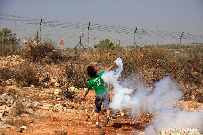 A Palestinian protestor hurls a tear gas canister back at Israeli troops during a demonstration against Israel's separation barrier in the West Bank village of Bilin near Ramallah, Friday,Nov. 4, 2010. Photo by Wagdi Esh...