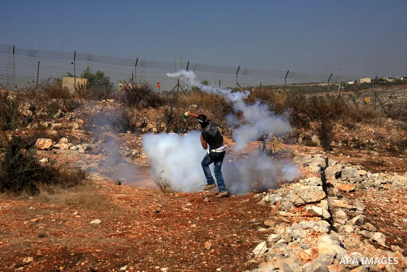 A Palestinian protestor hurls a tear gas canister back at Israeli troops during a demonstration against Israel's separation barrier in the West Bank village of Bilin near Ramallah, Friday,Nov. 4, 2010. Photo by Wagdi Esh...