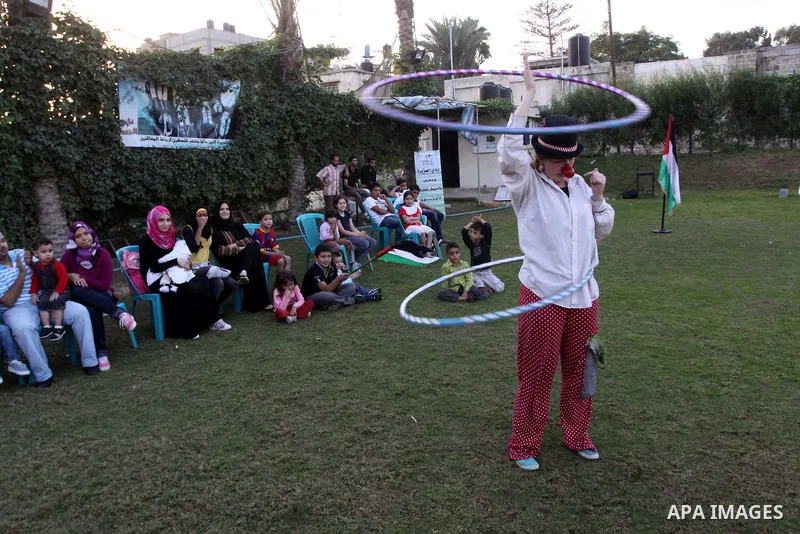Palestinians gather around members of the British Circus , dressed as clowns, during a performance at a park in Gaza city on Nov. 5, 2010. the British circus recently arrived to the Gaza Strip to present a circus games f...