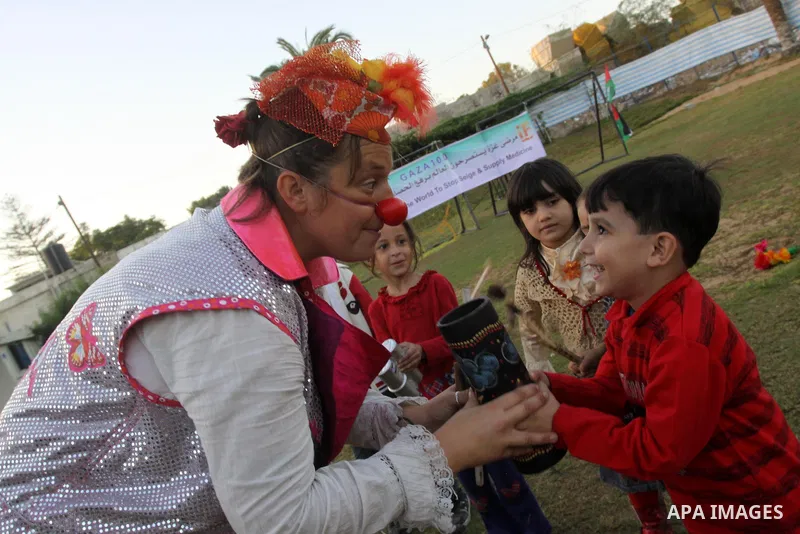Palestinians gather around members of the British Circus , dressed as clowns, during a performance at a park in Gaza city on Nov. 5, 2010. the British circus recently arrived to the Gaza Strip to present a circus games f...