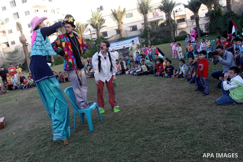 Palestinians gather around members of the British Circus , dressed as clowns, during a performance at a park in Gaza city on Nov. 5, 2010. the British circus recently arrived to the Gaza Strip to present a circus games f...