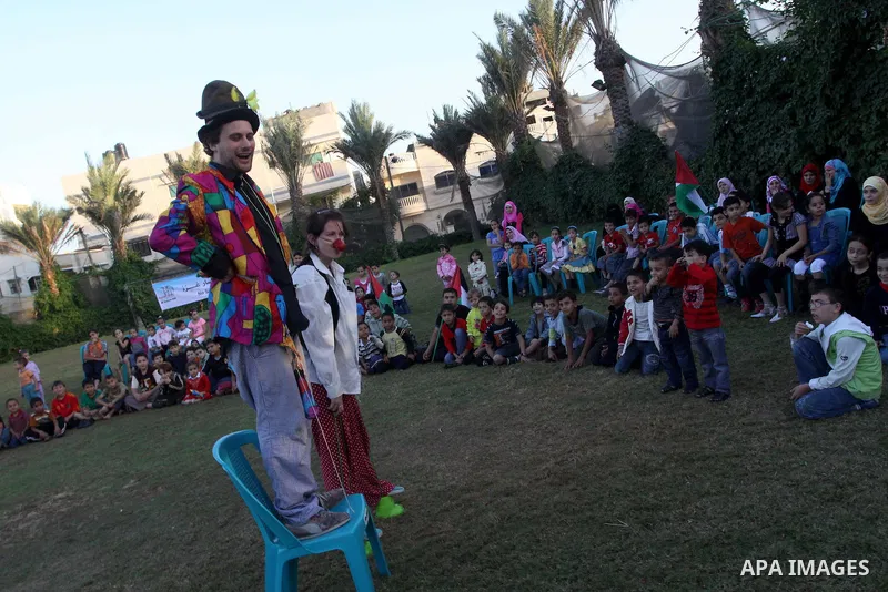 Palestinians gather around members of the British Circus , dressed as clowns, during a performance at a park in Gaza city on Nov. 5, 2010. the British circus recently arrived to the Gaza Strip to present a circus games f...