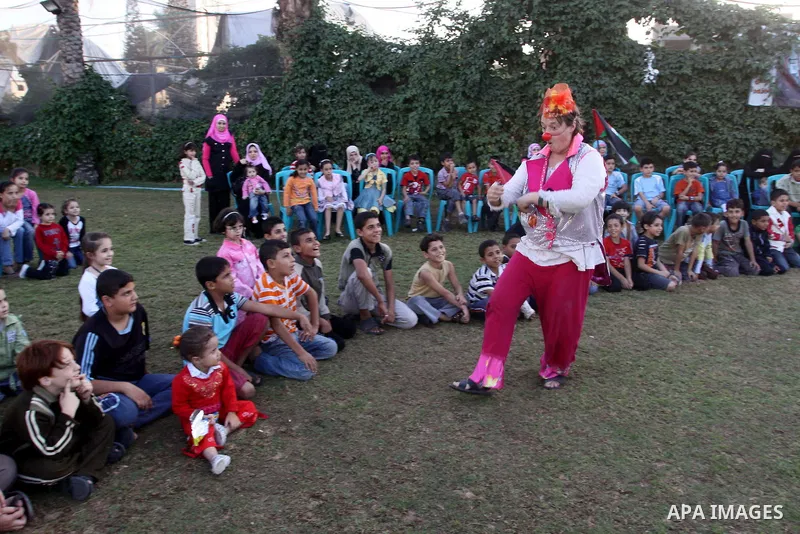 Palestinians gather around members of the British Circus , dressed as clowns, during a performance at a park in Gaza city on Nov. 5, 2010. the British circus recently arrived to the Gaza Strip to present a circus games f...