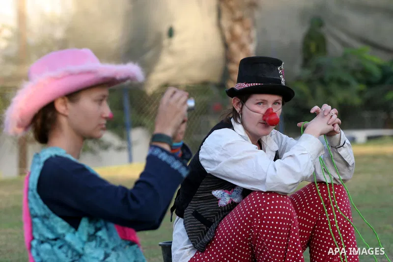Palestinians gather around members of the British Circus , dressed as clowns, during a performance at a park in Gaza city on Nov. 5, 2010. the British circus recently arrived to the Gaza Strip to present a circus games f...