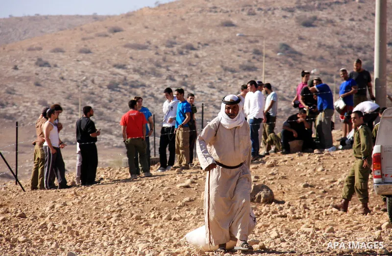 A Palestinian Bedouin leaves an area which was fenced off by Jewish settlers (background) as they try to take control of Palestinian land in the West Bank village of Tubas, near the Jordan Valley, on November 9, 2010. An...