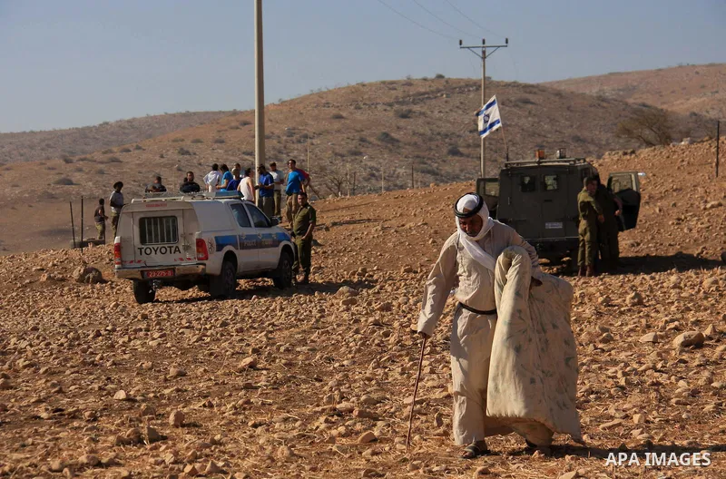 A Palestinian Bedouin leaves an area which was fenced off by Jewish settlers (background) as they try to take control of Palestinian land in the West Bank village of Tubas, near the Jordan Valley, on November 9, 2010. An...