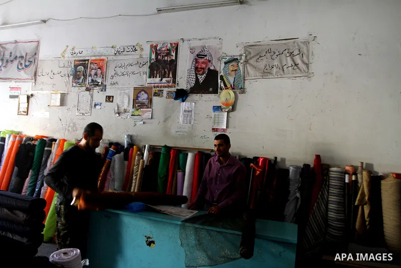 Palestinians work under a picture showing late Palestinian leader Yasser Arafat in Gaza City on November 11, 2010, as Palestinians mark the sixth anniversary of his death. Photo by Ashraf Amra