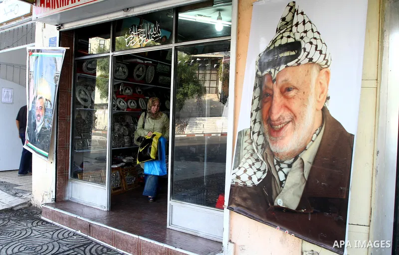 Palestinians walk past posters showing late Palestinian leader Yasser Arafat and Palestinian prime minister in Gaza Strip, Ismail Hanyeih in Gaza City on November 11, 2010, as Palestinians mark the sixth anniversary of h...