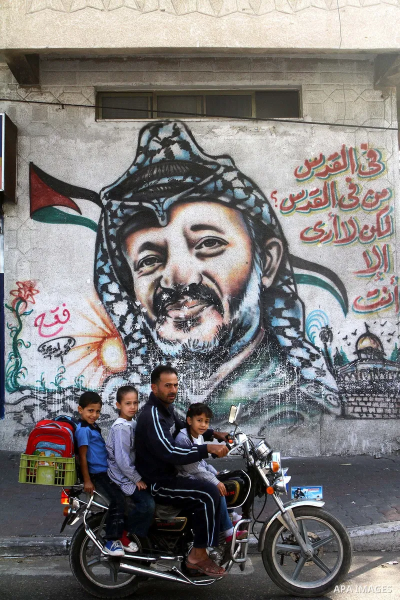 Palestinians walk past graffiti showing late Palestinian leader Yasser Arafat in Gaza City on November 11, 2010, as Palestinians mark the sixth anniversary of his death. Photo by Ashraf Amra