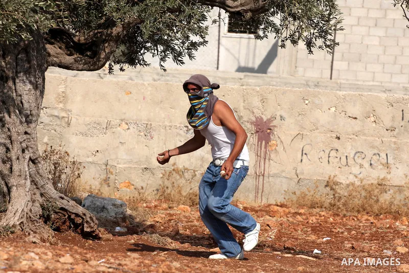 A Palestinian youth hurls stones towards Israeli soldiers during a protest against Israel's separation barrier as masked Palestinian stones throwers clash with Israeli soldiers in the West Bank village of Bilin, near Ram...
