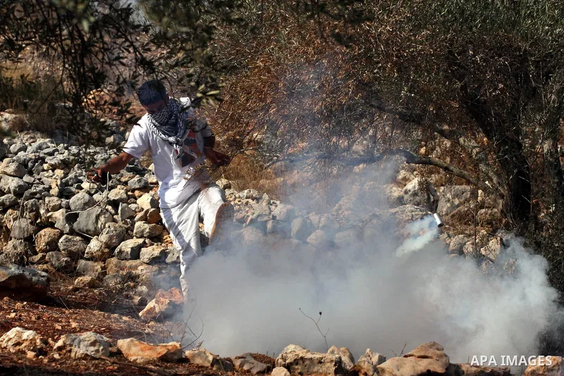 A Palestinian youth runs for cover from tear gas canister fired by Israeli soldiers during a protest against Israel's separation barrier as masked Palestinian stones throwers clash with Israeli soldiers in the West Bank...