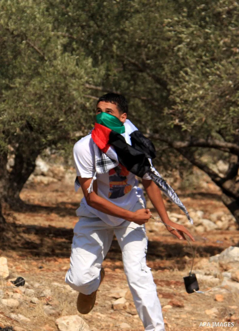 A Palestinian youth hurls stones towards Israeli soldiers during a protest against Israel's separation barrier as masked Palestinian stones throwers clash with Israeli soldiers in the West Bank village of Bilin, near Ram...