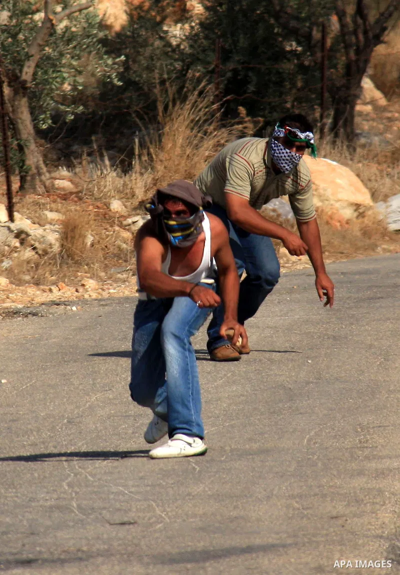 Palestinian youths hurl stones towards Israeli soldiers during a protest against Israel's separation barrier as masked Palestinian stones throwers clash with Israeli soldiers in the West Bank village of Bilin, near Ramal...