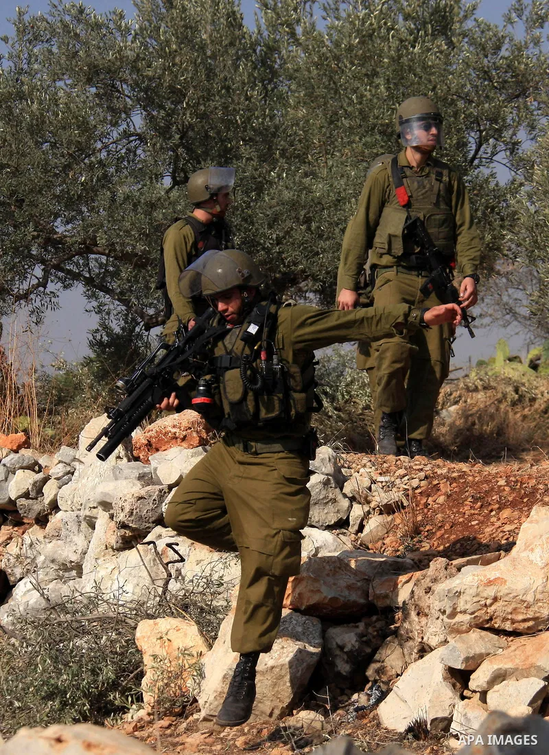 Israeli troops take position during a protest against Israel's separation barrier as masked Palestinian stones throwers clash with Israeli soldiers in the West Bank village of Bilin, near Ramallah, on November 12, 2010....
