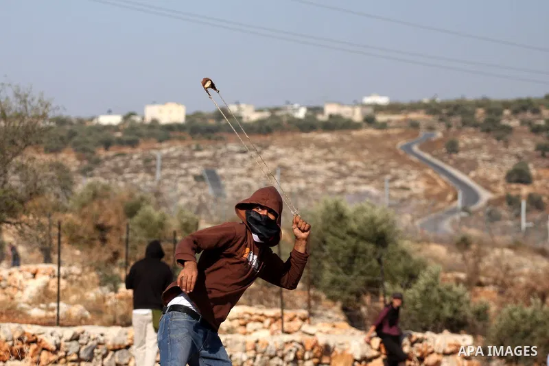 A Palestinian protester uses a slingshot to hurl stones towards Israeli soldiers during a protest against Israel's separation barrier in the West Bank village of Bilin near the West Bank city of Ramallah Nov. 18, 2010. P...