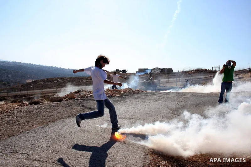 Palestinians run for cover from tear gas canisters fired by Israeli soldiers during a demonstration against Israel's separation barrier in the West Bank village of Bilin near the West Bank city of Ramallah Nov. 18, 2010....
