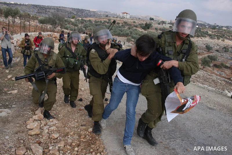 Israeli soldiers detain a demonstrator during a protest against the construction of the Israeli controversial separation barrier in the West Bank village of Bilin near Ramallah on, Dec. 10, 2010. Photo by Issam Rimawi