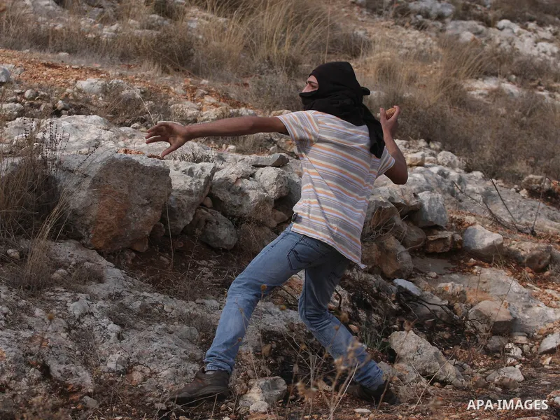 Palestinian protester hurls stones at Israeli troops during a protest against the construction of the Israeli controversial separation barrier in the West Bank village of Bilin near Ramallah on, Dec. 10, 2010. Photo by I...
