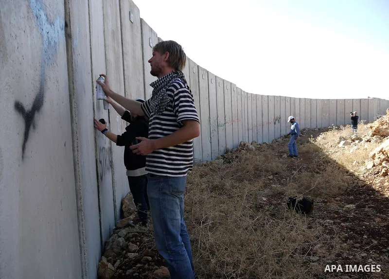 Foreign protesters paint on the wall during a weekly protest against Israel's separation barrier in the West Bank village of Nilin near Ramallah, Friday, Dec. 17, 2010. Israel says the barrier is necessary for security w...
