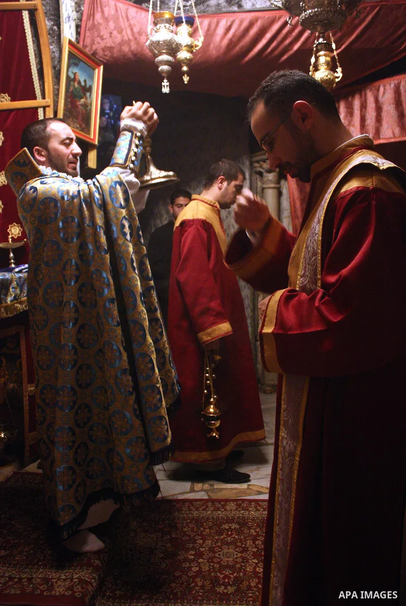 An Armenian Orthodox priest performs a mass in the 'Grotto,' or cave in the Church of the Nativity in the Church of the Nativity in the biblical West Bank city of Bethlehem on December 19, 2010 as part of the preparation...