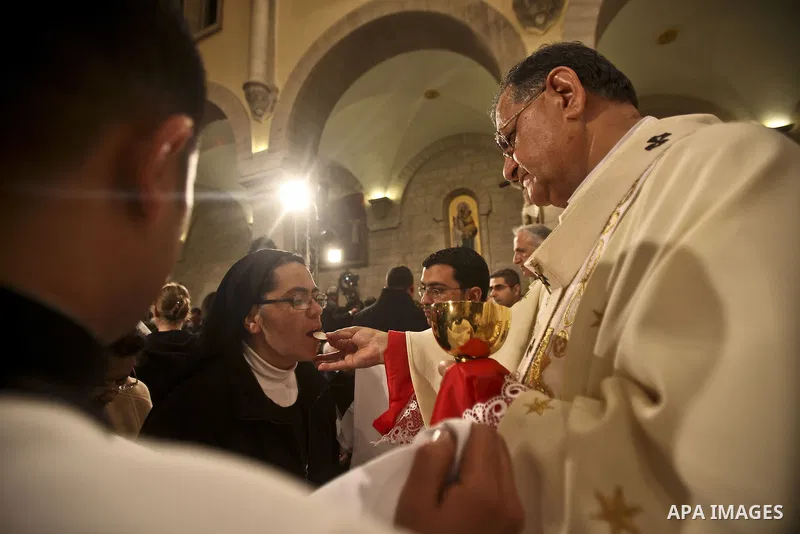 A Nun (L) recives a host from Latin Patriarch of Jerusalem Fouad Twal during Christmas midnight mass at the Church of the Nativity in the West Bank town of Bethlehem early Dec. 25, 2010. Photo by Fadi Arouri \ POOL