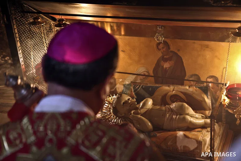 Latin Patriarch of Jerusalem Fouad Twal blesses a statue of the baby Jesus inside in the Grotto where Christians believe the Virgin Mary gave birth to Jesus, following the Christmas midnight mass at the Church of the Nat...