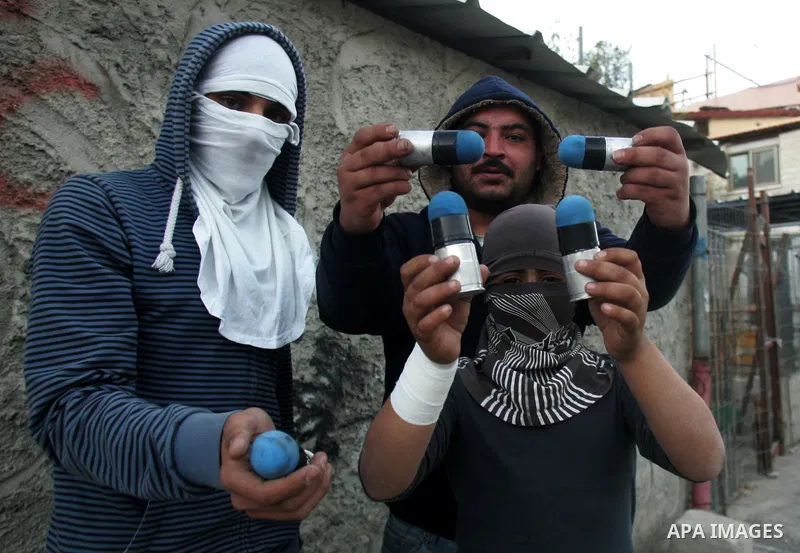 Palestinian youths hold tear gas canisters across the flashpoint Arab east Jerusalem district of Silwan during clashes with protesters against Jewish settlement in the neighbourhood on December 27, 2010, after the city's...
