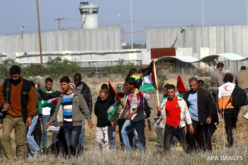 Palestinian protesters and foreign peace activists wave Palestinian national flags during a demonstration in front of the Erez crossing into Israel near the northern Gaza Strip town of Beit Hanun on December 28, 2010 to...