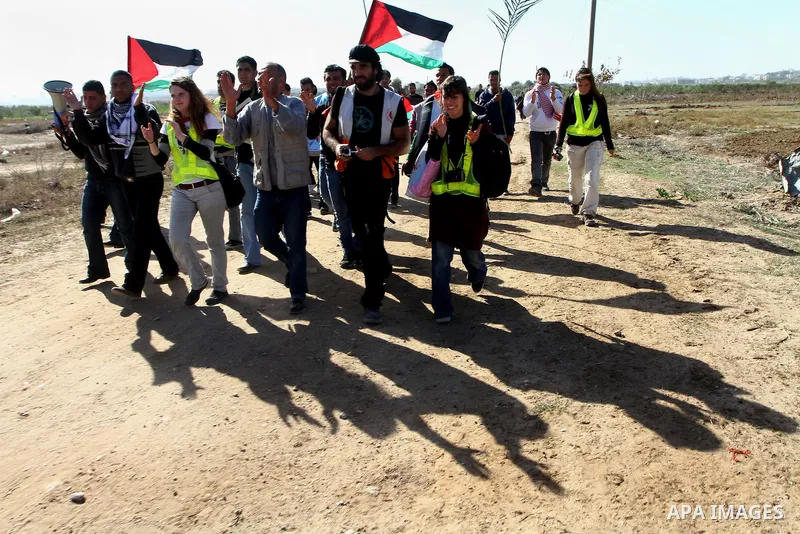 Palestinian protesters and foreign peace activists wave Palestinian national flags during a demonstration in front of the Erez crossing into Israel near the northern Gaza Strip town of Beit Hanun on December 28, 2010 to...