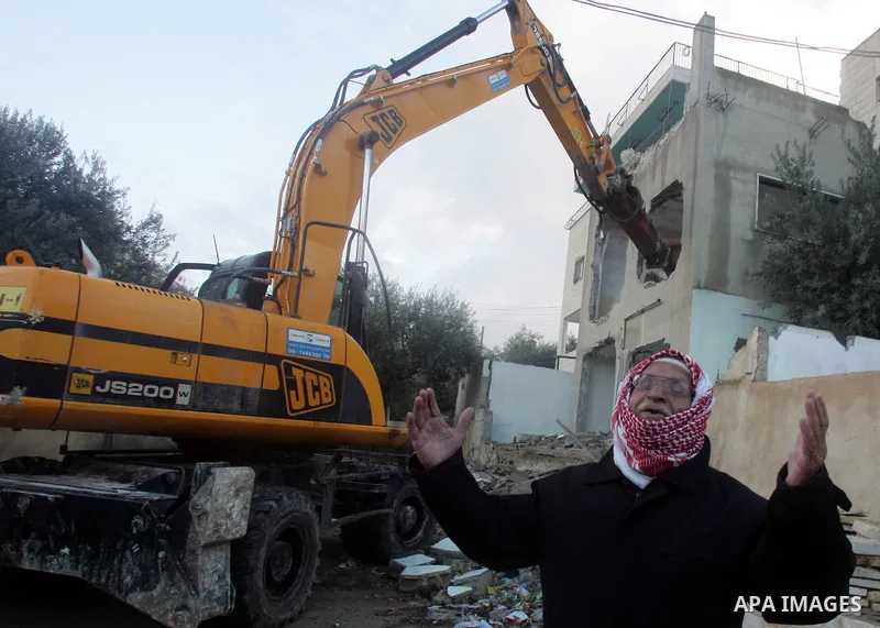 A Palestinian man stands next a bulldozer demolishing his house, Israeli army say that was built without a construction permit, in the Arab Jerusalem neighborhood of Sour Baher, on Dec. 31, 2010. Photo by Mahfouz Abu Tur...