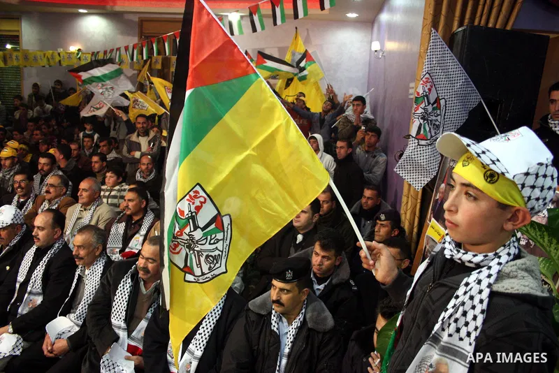 Palestinian supporters of Fatah wave the movement's flag and Palestinian flag during a rally marking the 46th anniversary of the secular party's creation in the village of Halhoul near the West Bank city of Hebron on Jan...