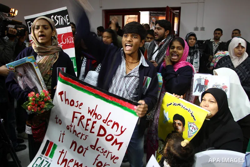 Members of the Asia 1 aid convoy holds placards during a rally at the ministry of prisoners in Gaza City on Jan. 3,2011. About 170 activists from over 15 Asian states crossed early Monday from Egypt into Gaza through Raf...