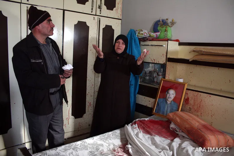The wife of 67-year-old Omar Kawasme stands near his picture and his blood-stained bed where she said he was killed by Israeli troops on January 7, 2010 in Hebron during a raid to arrest suspected militants. The shooting...