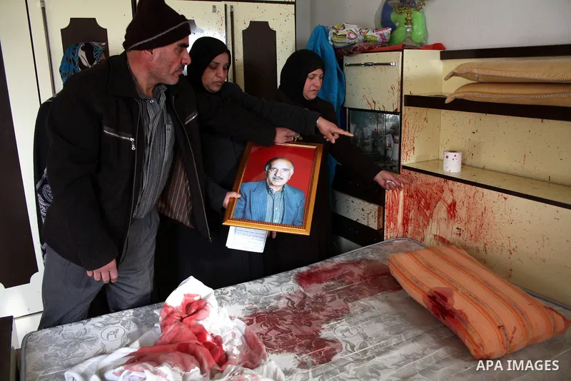 The wife of 67-year-old Omar Kawasme stands near his picture and his blood-stained bed where she said he was killed by Israeli troops on January 7, 2010 in Hebron during a raid to arrest suspected militants. The shooting...