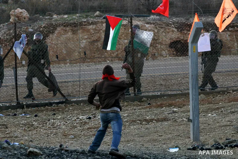 Palestinian youths hurl stones towards Israeli soldiers during a protest in the village of Bilin on January 7, 2011. Israeli troops in Hebron shot dead an elderly Palestinian civilian on Friday in a case of mistaken iden...