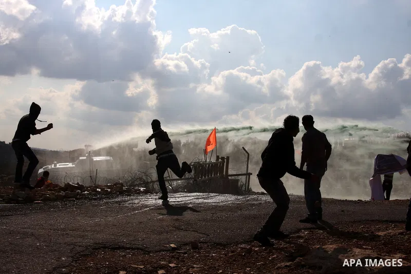 Palestinian youths hurl stones towards Israeli soldiers during a protest in the village of Bilin on January 7, 2011. Israeli troops in Hebron shot dead an elderly Palestinian civilian on Friday in a case of mistaken iden...