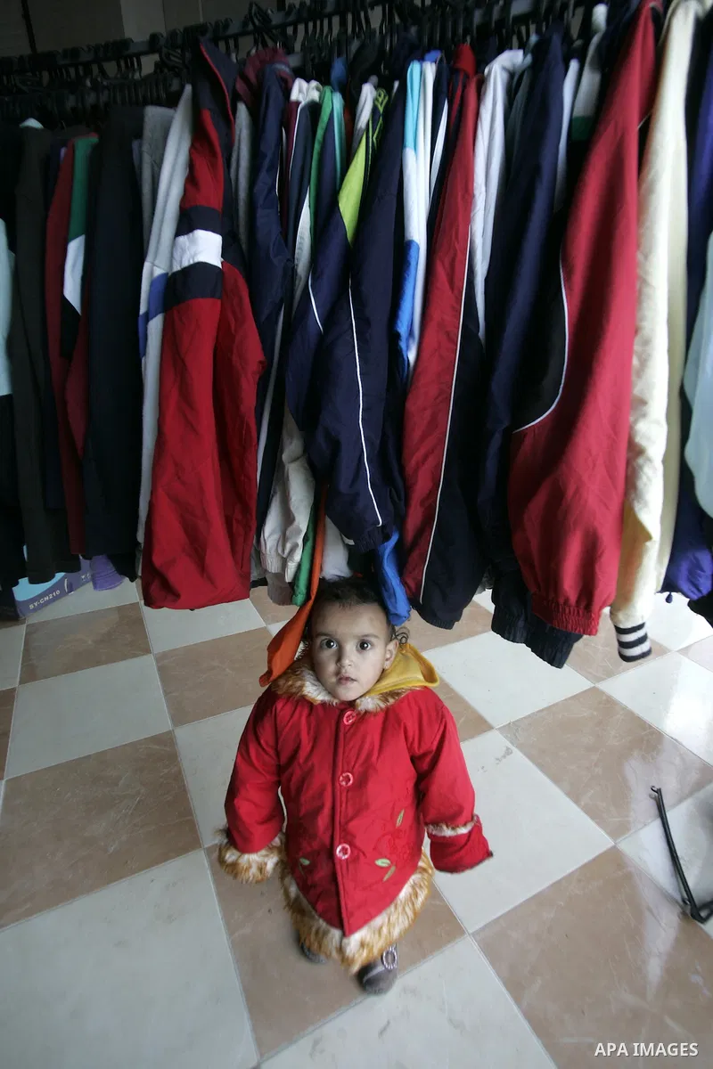 A Palestinian child stands under second-hand clothes at a shop in Rafah, southern Gaza Strip on January 08, 2011. Palestinians flock to buy used clothes known as (bale) that come from European countries and Israel becaus...