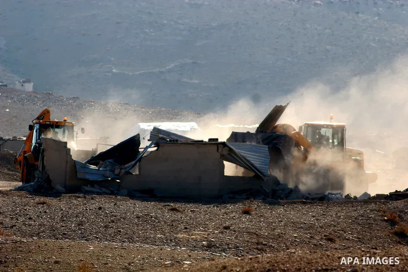 Israeli bulldozers demolish their house in the West Bank village of Yatta near Hebron on Jan. 12, 2011. Israeli Army pulled down Wednesday an elementary school and 17 homes lodging about 300 Bedouin persons near Hebron....