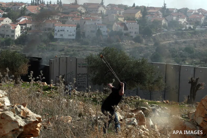 A Palestinian protester uses a slignshot to hurl a stone at Israeli troops, during a protest against Israel's separation barrier in the West Bank village of Nilin near Ramallah, Friday, Jan. 14, 2011. Photo by Issam Rima...