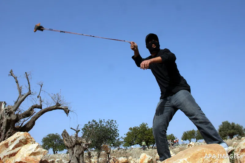 A Palestinian protester uses a slignshot to hurl a stone at Israeli troops, during a protest against Israel's separation barrier in the West Bank village of Nilin near Ramallah, Friday, Jan. 14, 2011. Photo by Issam Rima...