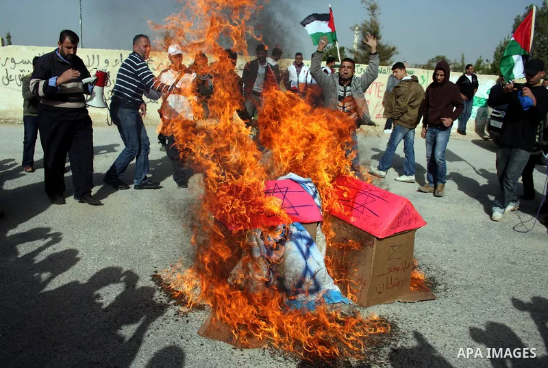 Palestinian demonstrators set a model of a Jewish settlement on fire before a protest against Israel's separation barrier in the West Bank village of Nilin near Ramallah, Friday, Jan. 14, 2011. Arabic on cardboard struct...
