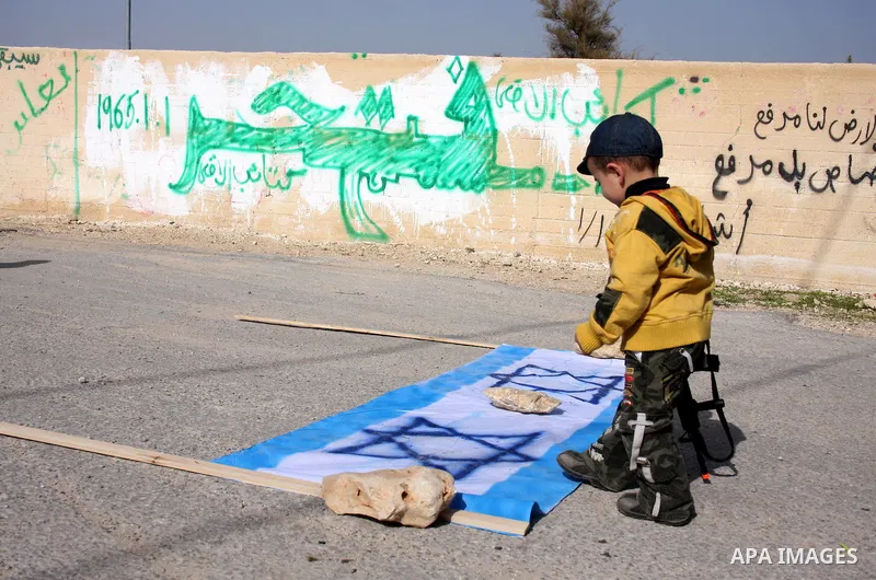 A Palestinian boy walks on an Israeli flag during a protest against Israel's separation barrier in the West Bank village of Nilin near Ramallah, Friday, Jan. 14, 2011. Photo by Issam Rimawi