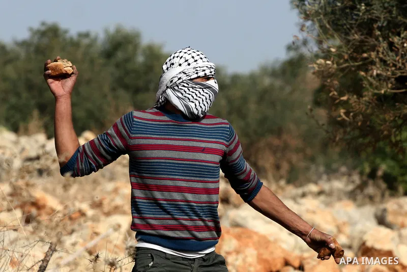 A Palestinian protester hurls a stone at Israeli troops, during a protest against Israel's separation barrier in the West Bank village of Nilin near Ramallah, Friday, Jan. 14, 2011. Photo by Issam Rimawi
