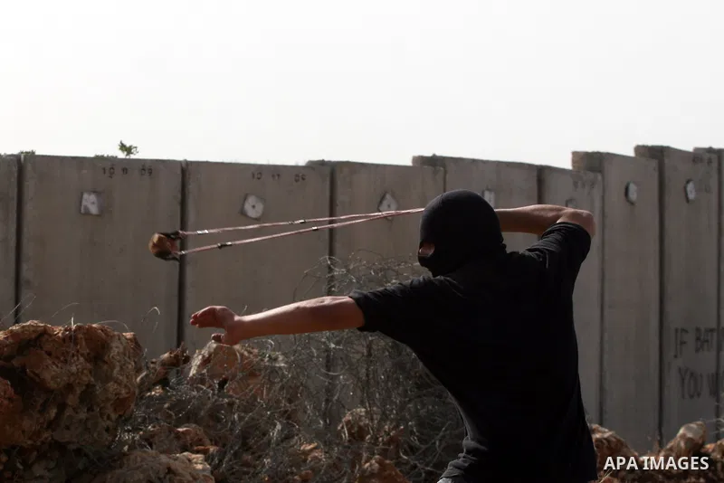 A Palestinian protester uses a slignshot to hurl a stone at Israeli troops, during a protest against Israel's separation barrier in the West Bank village of Nilin near Ramallah, Friday, Jan. 14, 2011. Photo by Issam Rima...