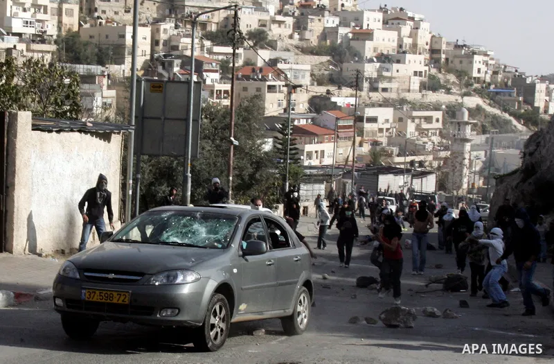 Palestinian youths hurl stones towards a Jewish settler car during clashes in the Arab east Jerusalem neighbourhood of Silwan against Jewish settlement activity in the Palestinian districts of the holy city on Jan. 14, 2...