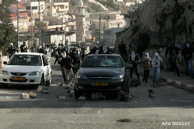 Palestinian youths hurl stones towards a Jewish settler car during clashes in the Arab east Jerusalem neighbourhood of Silwan against Jewish settlement activity in the Palestinian districts of the holy city on Jan. 14, 2...