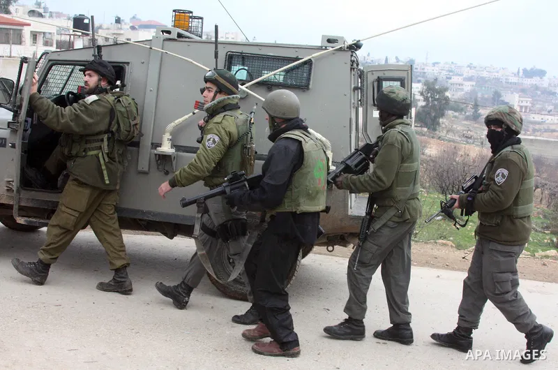 Israeli soldiers stand guard during a demonstration by Palestinian, Israeli and foreign activists against the demolishing of farm land to be used in the construction of Jewish settlements near the existing Israeli settle...