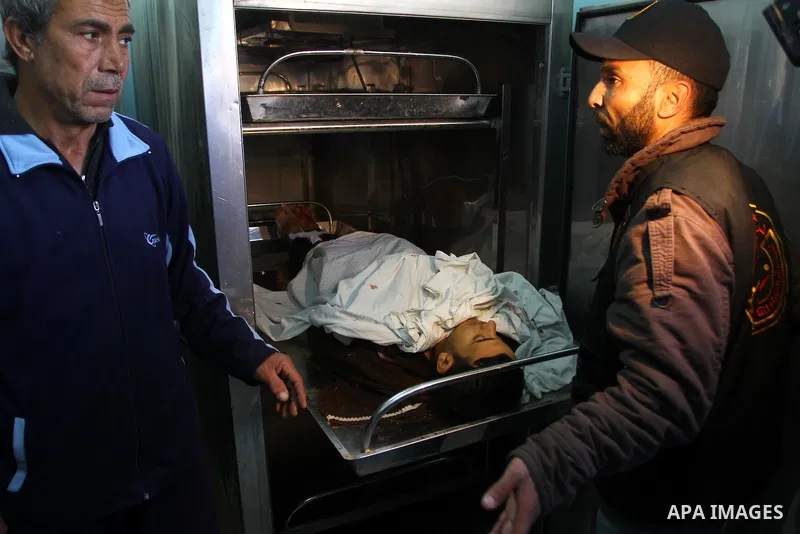 Palestinians look at the body of Amjad al-Zaaneen at a morgue in a hospital in the northern Gaza Strip town of Beit Hanon on Jan. 18,2011. An Israeli shell killed al-Zaaneen and injured two other, Palestinian hospital of...